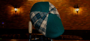 The Craic Cap is here, 8 panel cap with green and plaid fabric, shown hanging on a bar tap